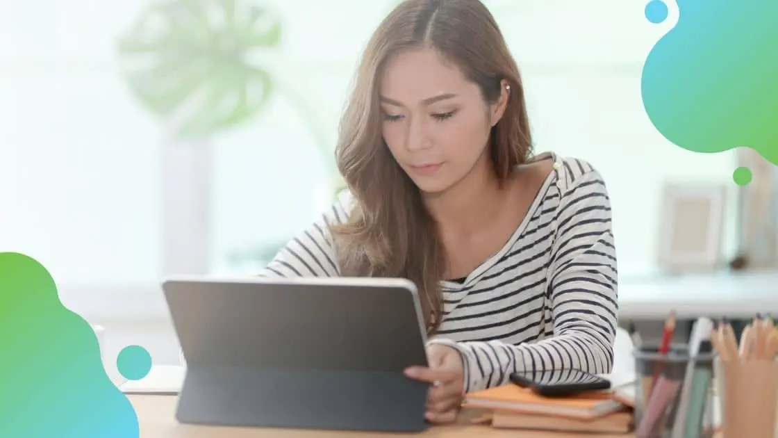 woman working remotely sitting at a desk using a tablet